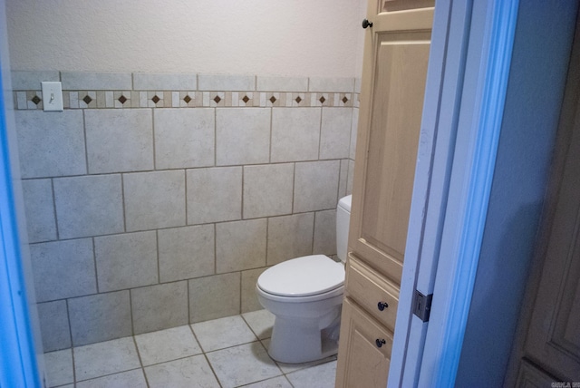 bathroom featuring tile patterned flooring, toilet, and tile walls