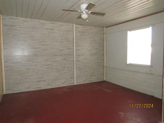 unfurnished room featuring ceiling fan and brick wall