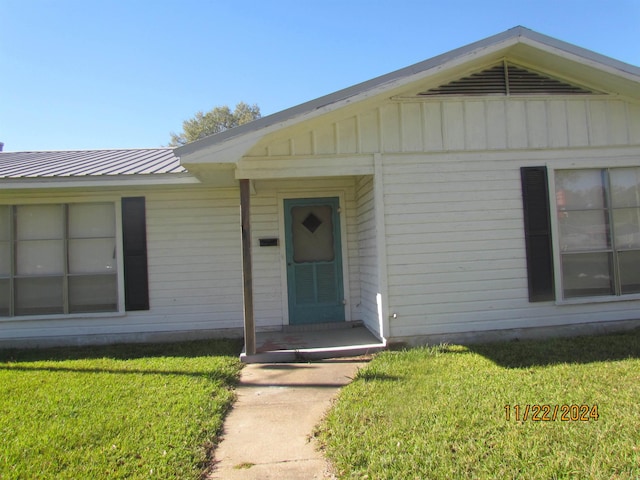 doorway to property with a lawn