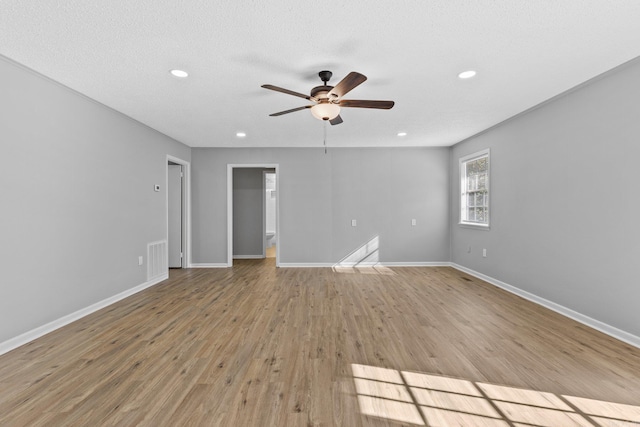 empty room with a textured ceiling, light hardwood / wood-style flooring, and ceiling fan