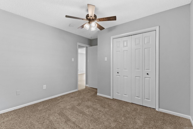 unfurnished bedroom with ceiling fan, a closet, carpet floors, and a textured ceiling