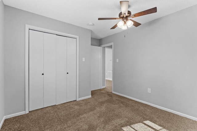 unfurnished bedroom featuring carpet, a closet, and ceiling fan