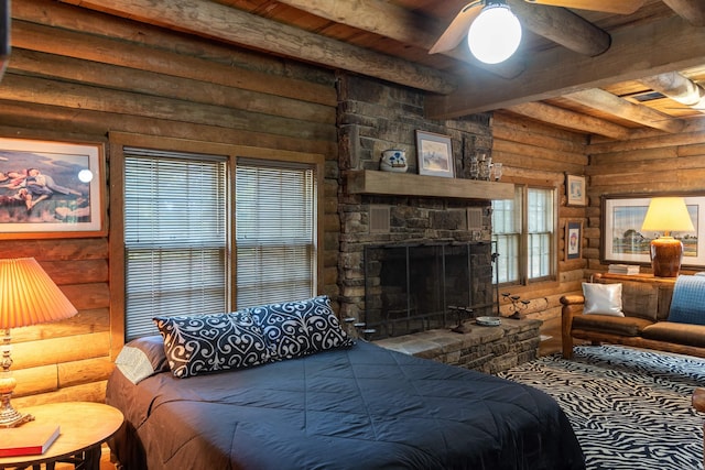 bedroom featuring beamed ceiling, a fireplace, ceiling fan, and rustic walls