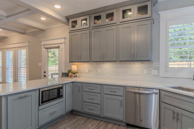 kitchen with beam ceiling, kitchen peninsula, backsplash, and appliances with stainless steel finishes