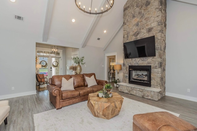 living room with french doors, hardwood / wood-style flooring, high vaulted ceiling, beamed ceiling, and a stone fireplace