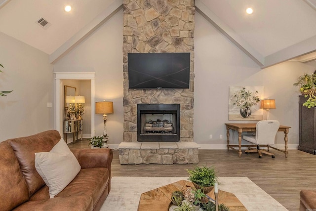 living room with a stone fireplace, beamed ceiling, high vaulted ceiling, and light hardwood / wood-style floors