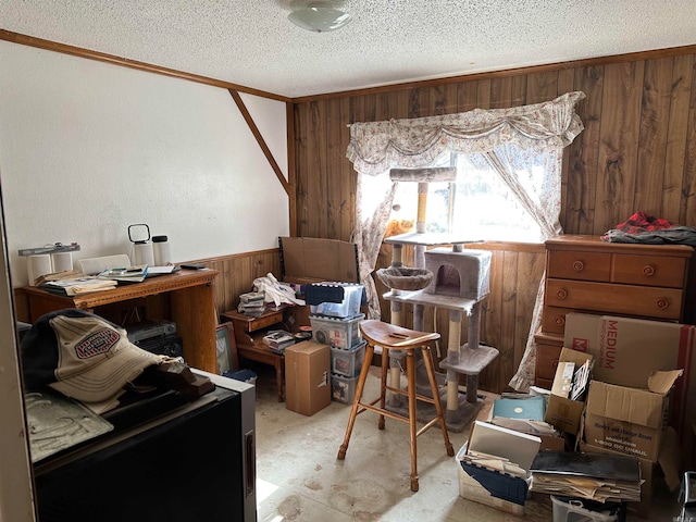 misc room featuring a textured ceiling, ornamental molding, and wood walls