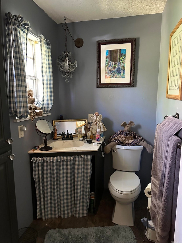 bathroom with vanity, toilet, and a textured ceiling