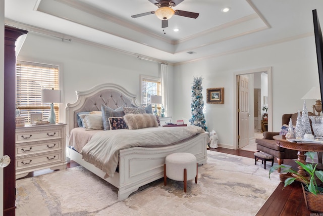 bedroom with connected bathroom, ceiling fan, a raised ceiling, wood-type flooring, and ornamental molding