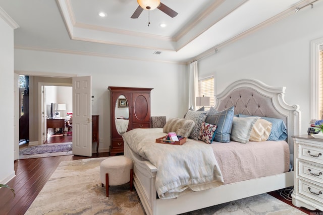 bedroom featuring dark hardwood / wood-style flooring, a raised ceiling, ceiling fan, and ornamental molding