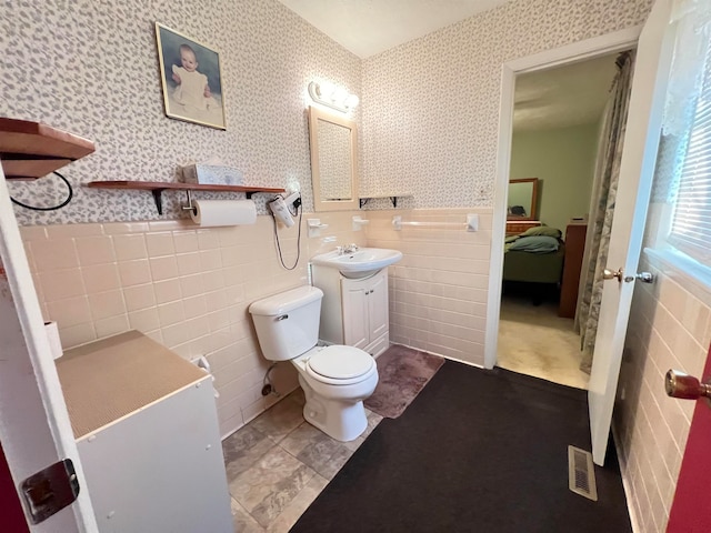 bathroom with vanity, toilet, and tile walls