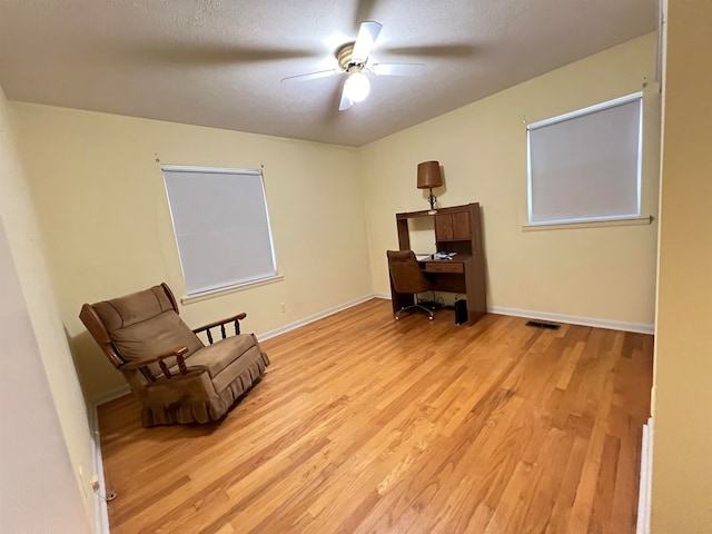 living area featuring ceiling fan, a textured ceiling, and light hardwood / wood-style flooring