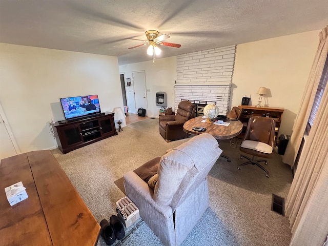 living room featuring a fireplace, a textured ceiling, carpet floors, and ceiling fan