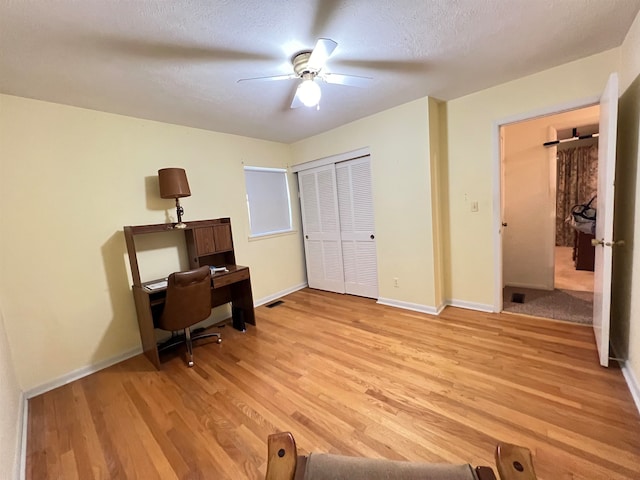 office featuring ceiling fan, light hardwood / wood-style floors, and a textured ceiling