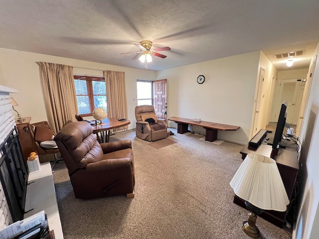 carpeted living room featuring ceiling fan and a textured ceiling