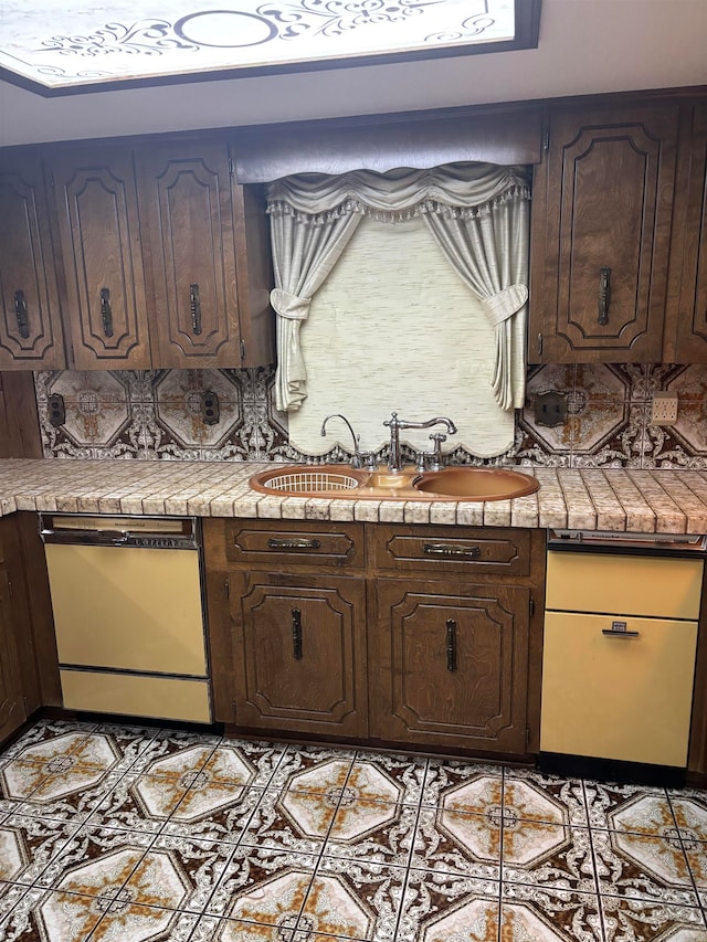 kitchen with dishwasher, dark brown cabinetry, light tile patterned flooring, and sink