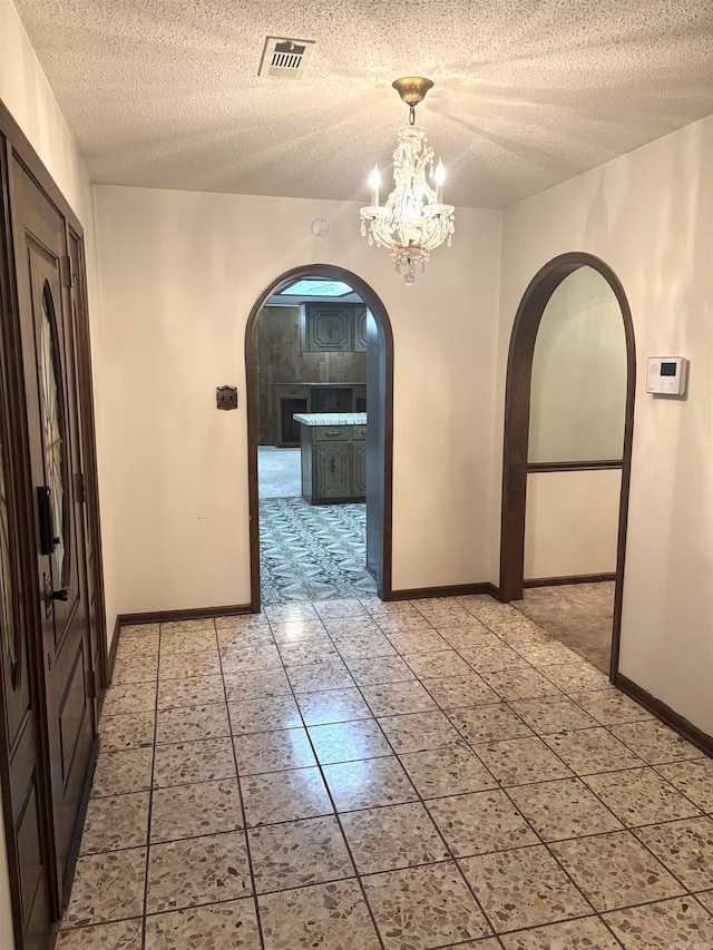 corridor with a textured ceiling and a notable chandelier