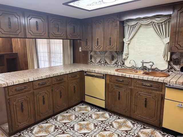 kitchen with dishwasher, dark brown cabinets, sink, and kitchen peninsula