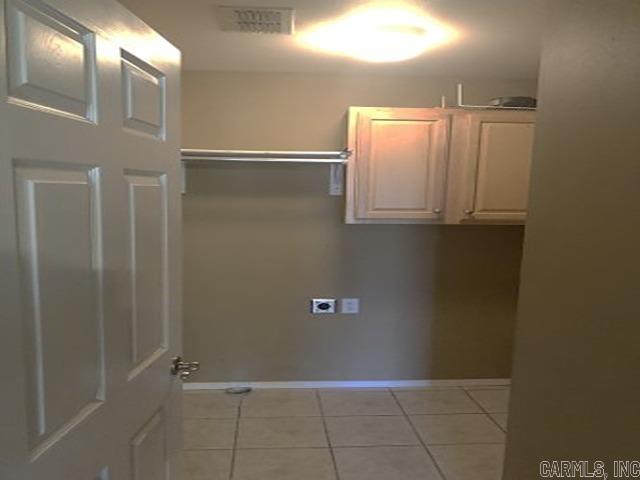 laundry room featuring hookup for an electric dryer, cabinets, and light tile patterned floors