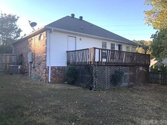 rear view of house featuring central air condition unit, a lawn, and a wooden deck