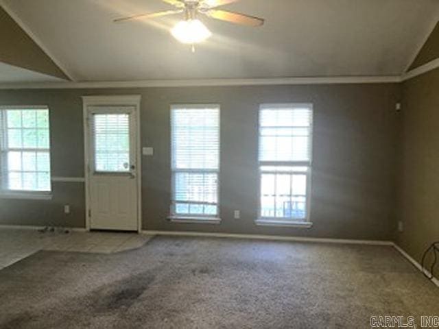 carpeted entrance foyer with ceiling fan, plenty of natural light, vaulted ceiling, and ornamental molding