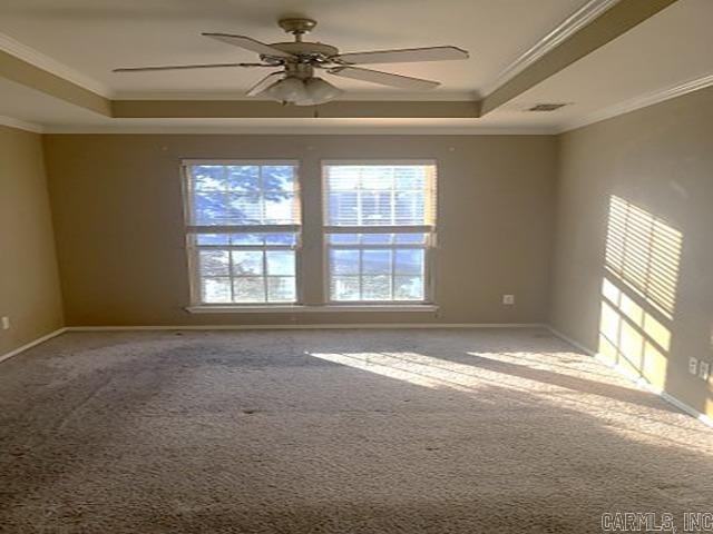 empty room with a raised ceiling, ceiling fan, and ornamental molding