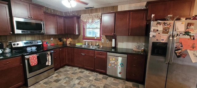 kitchen featuring a textured ceiling, ceiling fan, sink, and stainless steel appliances