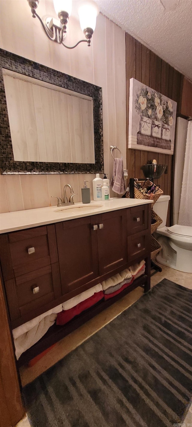 bathroom with vanity, a textured ceiling, toilet, and wood walls