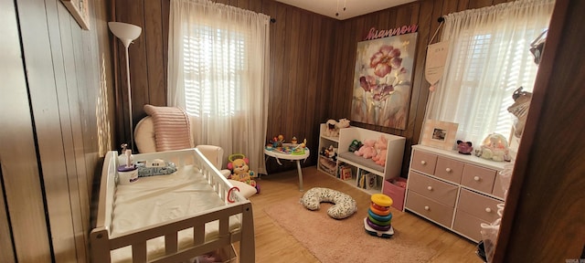 bedroom with wood walls and light hardwood / wood-style flooring