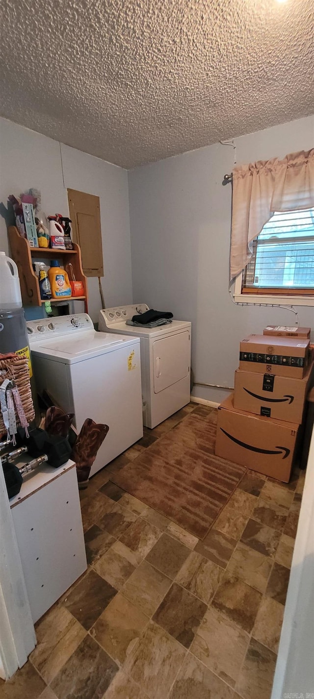 laundry room with a textured ceiling, electric panel, and washing machine and clothes dryer