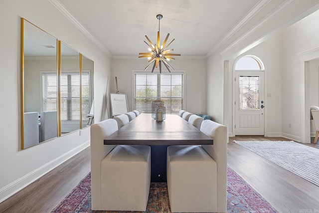 dining space featuring dark hardwood / wood-style flooring, ornamental molding, and an inviting chandelier