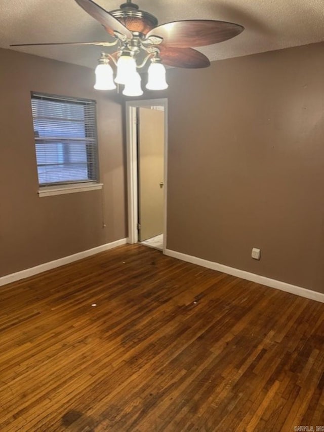 spare room with a textured ceiling, ceiling fan, and dark wood-type flooring