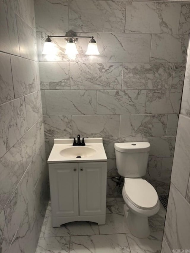 bathroom with vanity, tile walls, and toilet