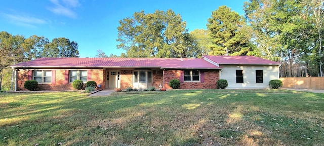 single story home featuring brick siding, fence, and a front lawn