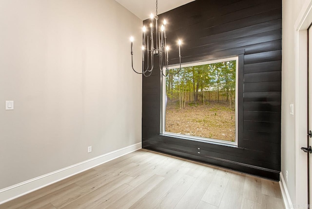 unfurnished dining area featuring a notable chandelier and light hardwood / wood-style flooring