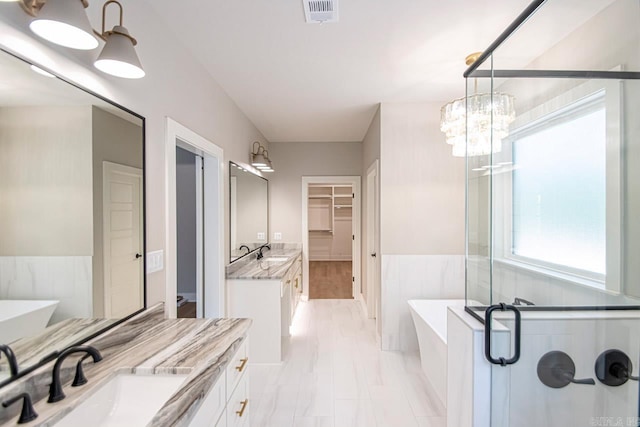 bathroom featuring plus walk in shower, vanity, and an inviting chandelier