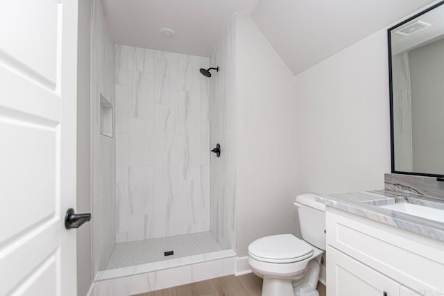 bathroom with tiled shower, hardwood / wood-style floors, vanity, and toilet