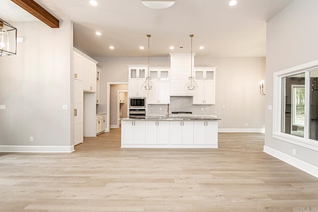 kitchen with stainless steel appliances, white cabinetry, a center island with sink, and hanging light fixtures