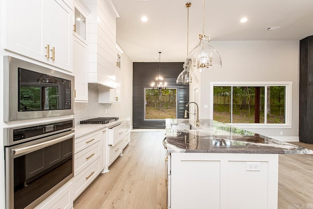 kitchen with a kitchen island with sink, white cabinets, sink, light hardwood / wood-style flooring, and stainless steel appliances