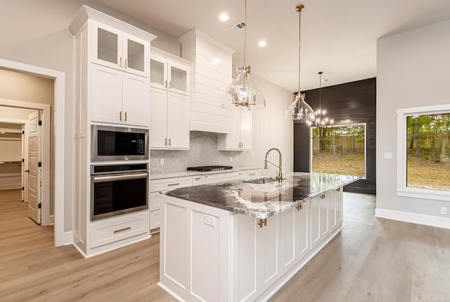 kitchen featuring a kitchen island with sink, sink, white cabinets, and stainless steel appliances