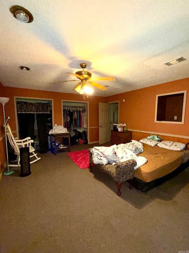 carpeted bedroom with ceiling fan, a textured ceiling, and a closet