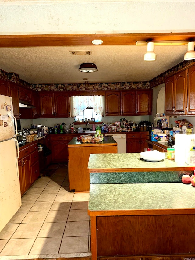 kitchen with a textured ceiling, a center island, light tile patterned floors, and white appliances