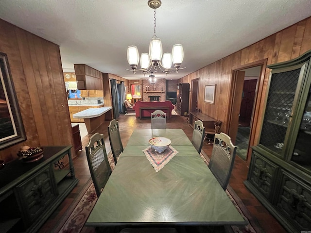 dining space featuring a chandelier, a textured ceiling, wooden walls, and billiards