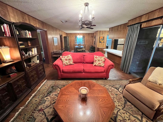 living room with wood walls, a textured ceiling, and a chandelier