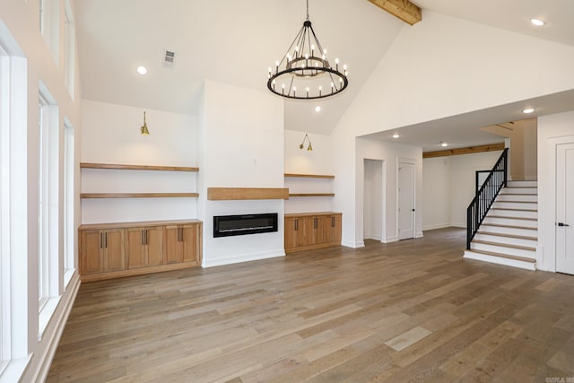 unfurnished living room featuring hardwood / wood-style floors, beam ceiling, high vaulted ceiling, and an inviting chandelier