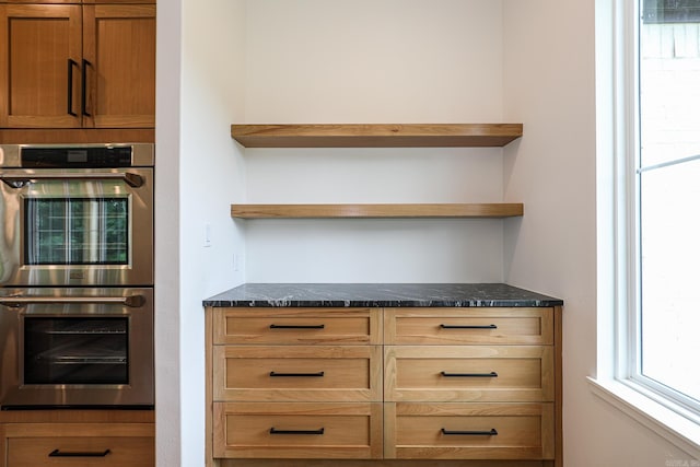 interior space featuring dark stone counters and stainless steel double oven