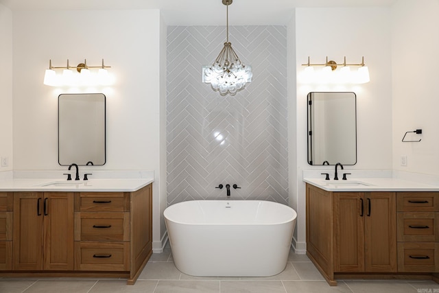 bathroom with a chandelier, vanity, tile patterned floors, and a bathtub