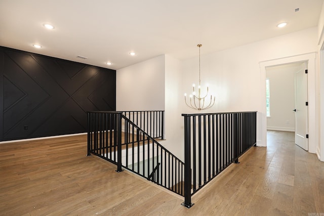 hallway with light hardwood / wood-style floors and an inviting chandelier