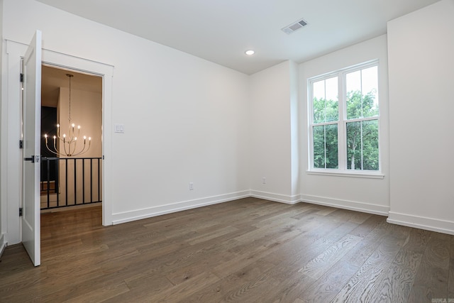 empty room featuring dark hardwood / wood-style floors and a notable chandelier