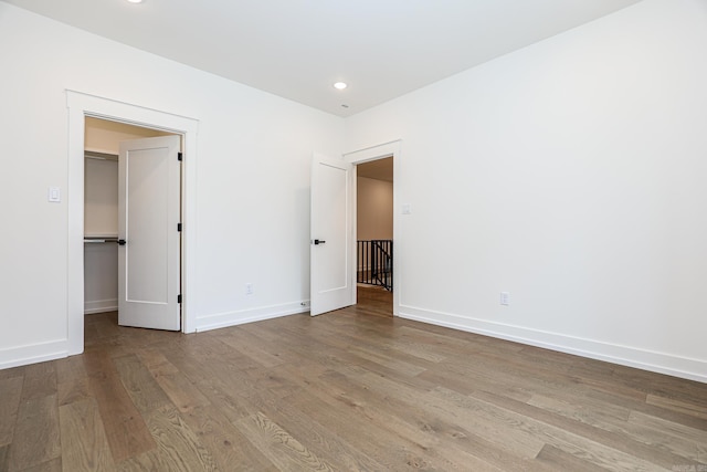 unfurnished bedroom with light hardwood / wood-style floors, a walk in closet, and a closet